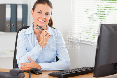 Woman sitting behind her desk holding glasses