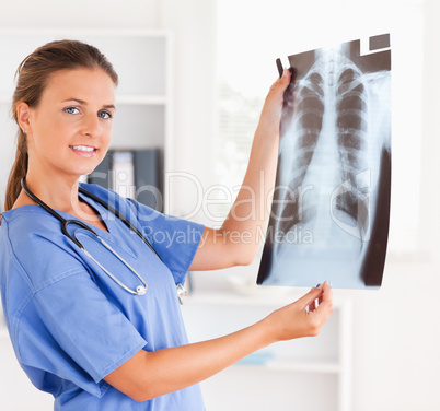 Gorgeous doctor with stethoscope and x-ray looking into camera