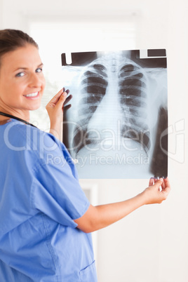 Charming doctor smiling at the camera holding a x-ray