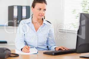 Businesswoman sitting behind her desk looking at her screen