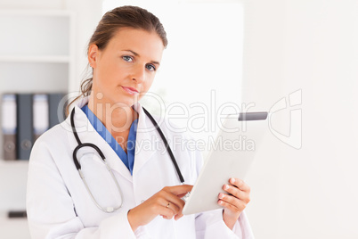 Charming doctor having a stethoscope around her neck pointing at