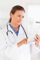 Charming doctor with  a stethoscope pointing at a file