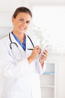 Portrait of a smiling doctor writing something down looking into