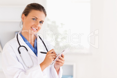Concentrated doctor writing something down looking into the came