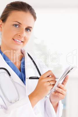 Portrait of a smiling doctor writing something down while lookin