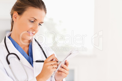 Close up of a smiling brunette doctor writing something down