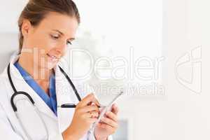 Close up of a smiling brunette doctor writing something down