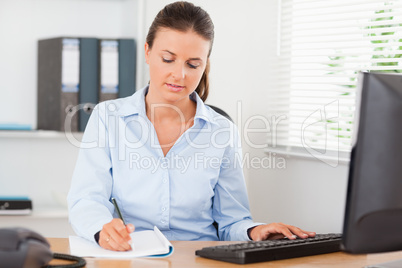 Concentrated businesswoman writing something down