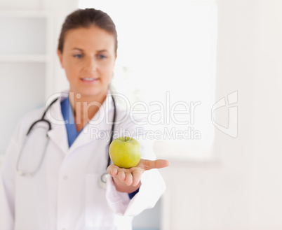 Good looking brunette doctor with stethoscope looking at an appl