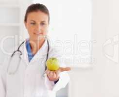 Good looking brunette doctor with stethoscope looking at an appl
