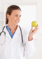 Gorgeous doctor looking at a green apple