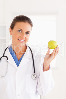 Gorgeous brunette doctor looking at a green apple