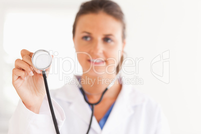 gorgeous brunette doctor showing stethoscope to the camera