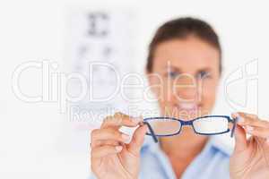 Portrait of a brunette eye specialist handing out glasses smilin