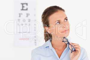 Thinking eye specialist holding glasses