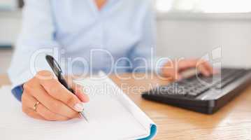 gorgeous brunette businesswoman typing and writing