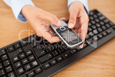 Woman holding mobile phone above keyboard