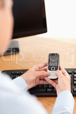 A businesswoman holding a mobile phone at workplace