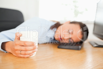 Sleeping businesswoman with coffee in office