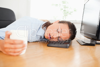 Sleeiping woman in an office holding coffee