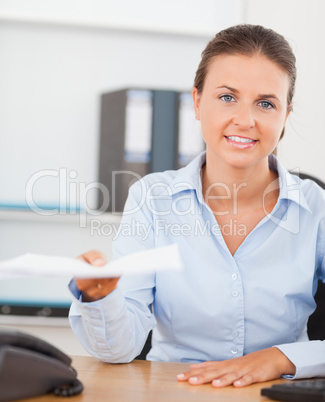 Charming brunette businesswoman handing out a paper