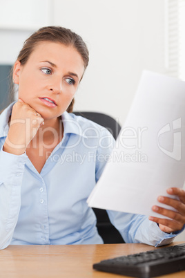 Charming brunette businesswoman looking at a paper