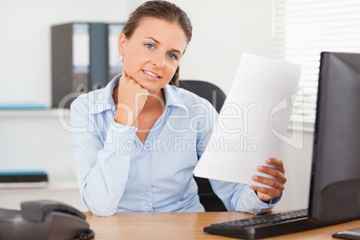 Charming businesswoman holding a paper looking into the camera