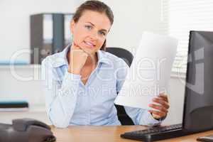 Charming businesswoman holding a paper looking into the camera