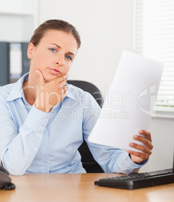 Close up of a thinking businesswoman holding a paper