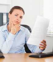 Close up of a thinking businesswoman holding a paper