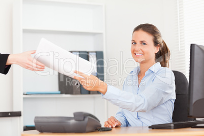 smiling businesswoman receiving a pile of paper looking into the smiling businesswoman receiving a pile of paper looking into the