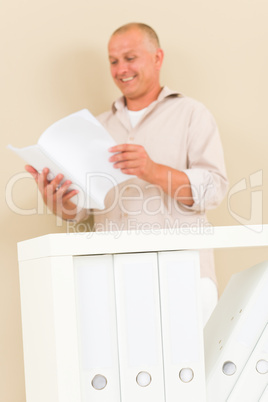 Casual businessman mature stand behind bookshelf