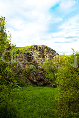 rock with green against the blue sky with clouds