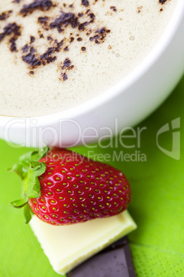 cup of cappuccino with chocolate and strawberry on a napkin