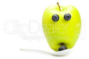 green apple with eyes of blueberries isolated on white