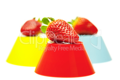 strawberries and colored bowls isolated on white