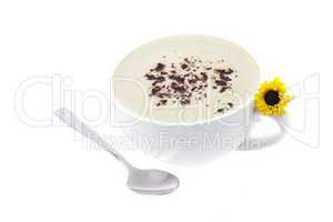 a cup of cappuccino with a spoon and a flower isolated on white