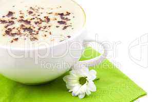 Cappuccino on the green cloth with flower isolated on white