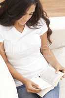 Hispanic Woman Reading Paperback Book at Home