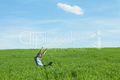 young man uses a laptop in the green field