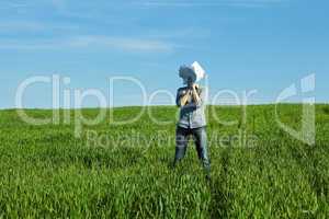 young man covering the face paper in green field