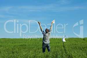 young man throwing a paper in the green field