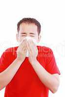 Young man with a cold blowing nose on tissue .