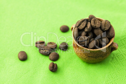 small jar with coffee beans on green background