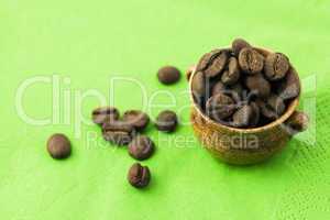 small jar with coffee beans on green background