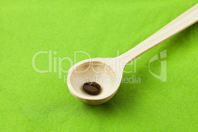 coffee beans in a wooden spoon on a green background
