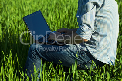 young man using laptop in the field