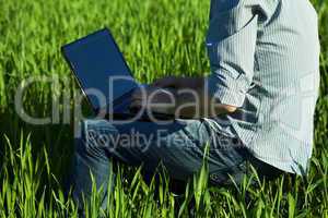 young man using laptop in the field