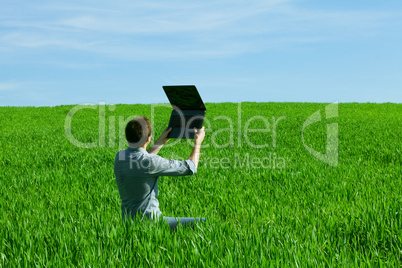 young man using laptop in the field