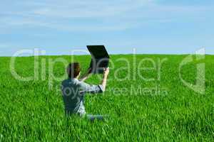 young man using laptop in the field